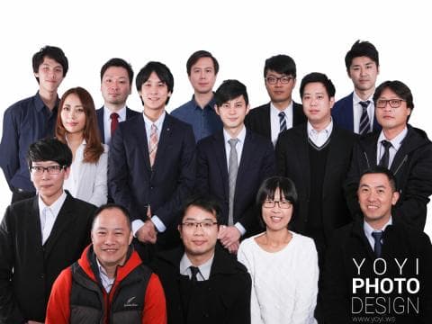 這張「團體照」的照片是一群穿著正式服裝的男性和女性，他們站在一起，背景是白色，照片中有一家公司的標誌和網站地址。