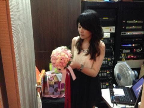 這張照片是一個穿著白色洋裝的女孩，她拿著一束粉紅色的花，站在一個房間裡。