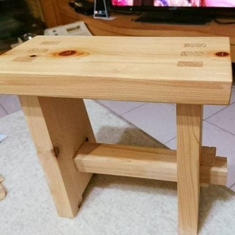 這張照片是一個木製的凳子，凳子上有三個木頭拼接的結構，看起來很牢固。