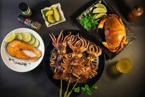 這張「海鮮大餐」的照片是烤魷魚、烤鮭魚和螃蟹，還有檸檬和香料。