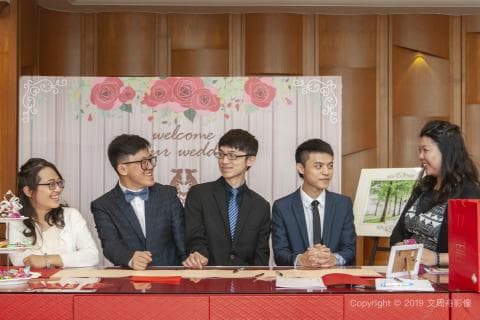 這張照片是四個朋友在婚禮上一起拍照，其中一位女士穿著白色洋裝，其他三位男士都穿著西裝。他們看起來很開心，準備好迎接婚禮的開始。