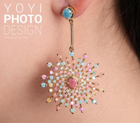 這張照片是一隻以粉紅色、黃色、藍色和綠色水晶製成的耳環。耳環的形狀像一個太陽，中間有一顆粉紅色的水晶。