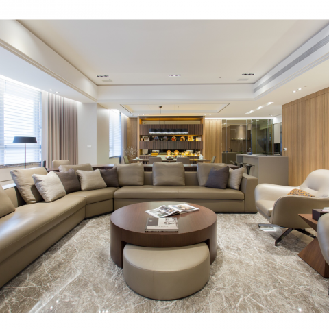 這張照片是一間現代風格的客廳，照片中最重要的部分是大型的皮質沙發，以及擺放在中間的木製圓形茶几。沙發看起來很舒適，茶几上擺放著幾本書，整體風格簡潔優雅。