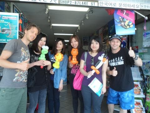 這張照片是一群朋友在店門口玩耍，他們各自拿著氣球，看起來很開心。