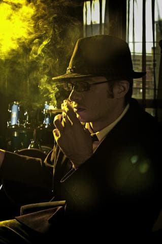 這張「一位戴著帽子、抽著煙的男人坐在椅子上」的照片是。