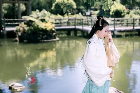 這張「女子穿著白色漢服，手持一把竹製油紙傘，站在池塘邊」的照片是。