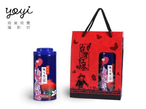 這張照片是一盒茶葉禮盒，禮盒是紅色，上面印著蝴蝶和花朵，禮盒裡裝著一罐茶葉，茶罐是藍色的，上面印著一個穿著傳統服裝的女孩，女孩的旁邊印著「東方美人茶」四個字。