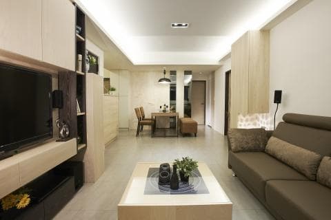 這張照片是一間現代化客廳，主要展現了沙發區的舒適和寬敞感。沙發由柔軟的布料製成，搭配深色系，帶給人一種放鬆和舒適的氛圍。牆面以淺色系為主，營造出明亮和寬敞的空間。