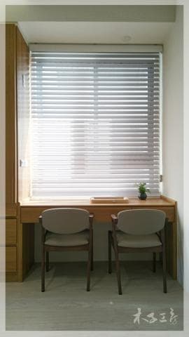 這張照片是一個有著木質書桌和兩張椅子的窗戶。 書桌和椅子都採用簡約的設計，並且與窗戶的木質百葉窗相呼應。