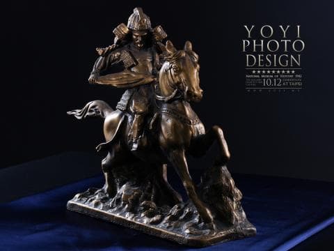 這張「騎馬武士」的照片是一個青銅雕像，描繪了一位身穿盔甲的武士騎在一匹駿馬上。武士的手裡握著一把劍，他的眼神堅定，顯示出他的勇氣和力量。雕像的細節非常精緻，從武士的盔甲到馬的鬃毛，都栩栩如生。雕像整體的氣勢雄偉，令人敬畏。