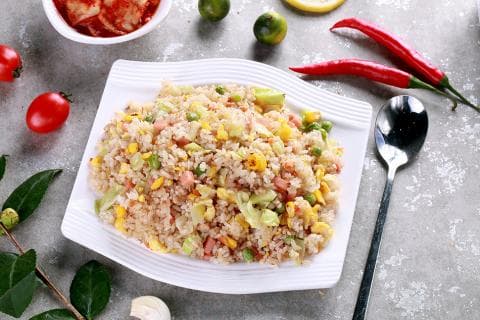 這張照片是一盤美味的炒飯，裡面的米飯粒粒分明，配料豐富，有玉米粒、青菜、肉末，看起來非常香，令人食指大動。