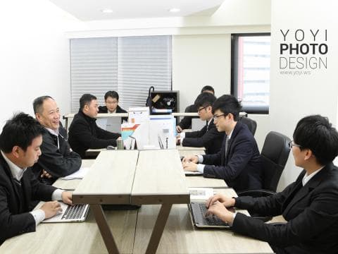 這張「會議室」的照片是幾位男士在開會，他們圍著一張桌子，桌子上放著筆記本電腦和文件。