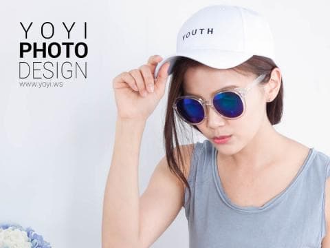 這張照片是一名年輕女子戴著白色棒球帽和藍色鏡片太陽眼鏡，看起來非常時尚。