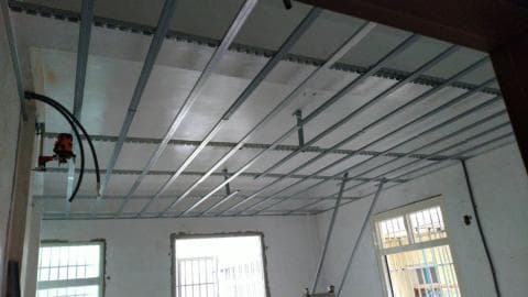 這張照片是一間正在裝修的房間，最重要的是天花板的框架，框架是由許多金屬條組成，並以網格狀排列，看起來非常堅固，未來將會裝上天花板板。