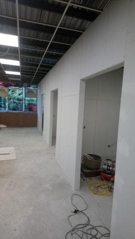 這張照片是一間正在裝修的房間，房間裏有一條電線在角落，上面連着一個插頭。