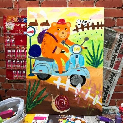 這張照片是一幅熊騎著摩托車的畫作，背景是鄉村風景。畫中熊戴著帽子，騎著一輛藍色的摩托車，背景有房屋、籬笆和綠草，畫面生動活潑。