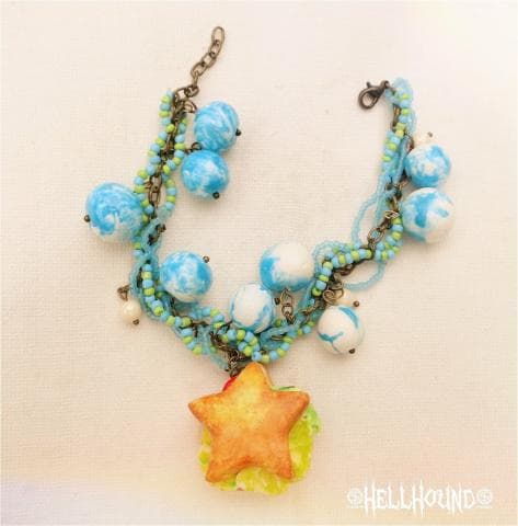 這張「手鍊」的照片是一條由多條鏈子和藍色、白色珠子串成的，中間垂著一顆黃色的星星形狀裝飾。