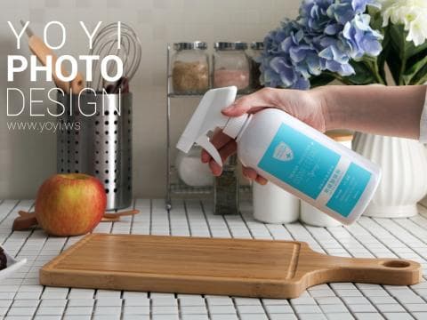 這張照片是一隻手正拿著一瓶噴霧清潔劑，準備噴灑在砧板上。