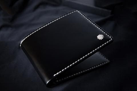 這張照片是一個黑色皮革錢包，錢包上有一個銀色的裝飾品。