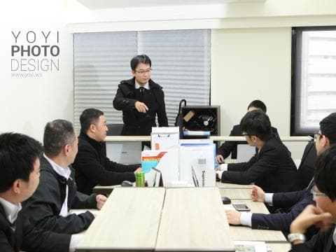 這張「辦公室會議」的照片是幾位男士在會議室裡開會，他們圍著一張桌子，桌上擺著筆記本電腦和文件。其中一位男士正在做簡報，其他男士則認真聆聽。