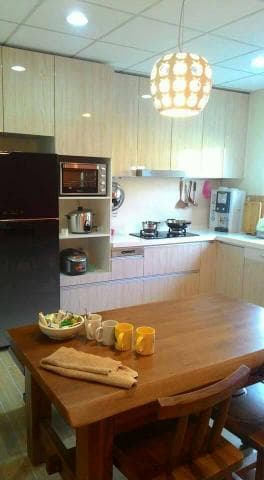 這張照片是一個現代化的廚房，最重要的部分是中間的餐桌。餐桌是用深色木頭做成的，上面擺放著四個杯子，看起來非常舒適。