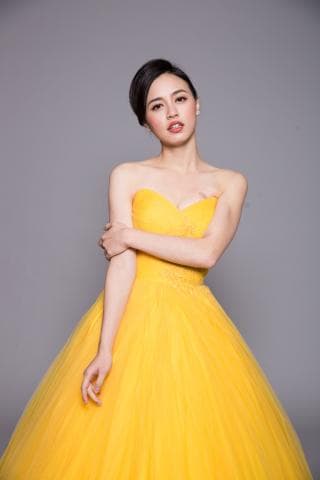 這張「婚紗照」的照片是一個穿著黃色蓬蓬裙婚紗的新娘，她有著黑色的頭髮，看起來很漂亮。