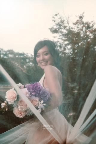 這張照片是一個穿著婚紗的女孩，她手裡拿著一個花束，並露出燦爛的笑容。