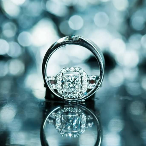 這張照片是一對閃閃發光的鑽戒，戒指的設計精美，鑲嵌著一顆明亮的方形鑽石，周圍環繞著細緻的鑽石邊框。