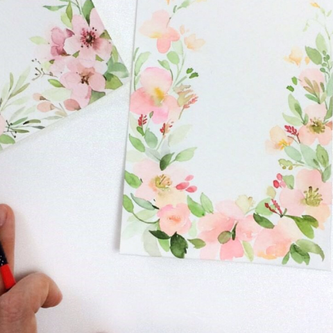 這張照片是一張以淡粉色花朵和綠葉為主題的水彩畫。畫中以花朵和綠葉圍成圓形，中間留白，顯得清新雅緻。