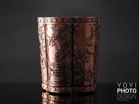 這張照片是一件精緻的銅製花瓶，瓶身刻有精美的花卉、鳥類和山水圖案，充滿了中國傳統文化的氣息，展現出中國古代的工藝水平。