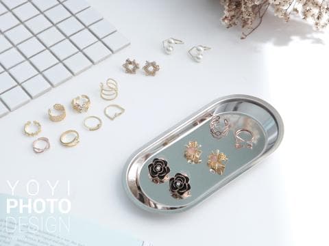 這張照片是一張銀色託盤，上面擺放著許多金屬飾品，有戒指、耳環、項鍊等。這些飾品設計精緻，閃閃發光，十分引人注目。