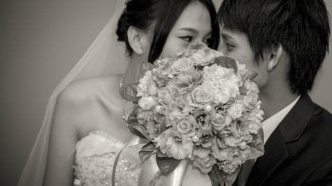 這張照片是一對新人在婚禮上擁抱，新娘穿著婚紗，新郎穿著西裝，他們手裡拿著一個巨大的花束，臉上帶著幸福的笑容。