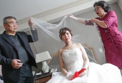 這張照片是一對新人婚禮的現場。新娘穿著白紗，新郎則穿著西裝，他們在婚禮的儀式中互相交換戒指，看起來非常甜蜜幸福。