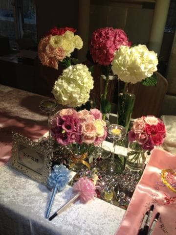 這張照片是一張擺放著各種顏色花朵的餐桌，桌上放著兩個裝飾性的小掃帚。