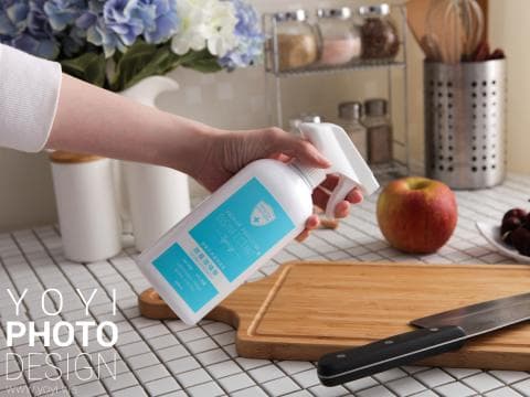 這張「廚房」的照片是，一個人在廚房用消毒噴霧清潔木質砧板，旁邊還有蘋果和刀子。