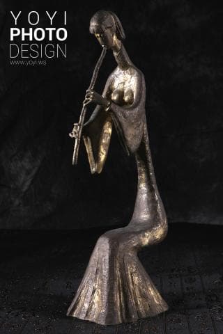 這張「雕塑」的照片是一個穿著長袍的女性，她正在演奏一種樂器。