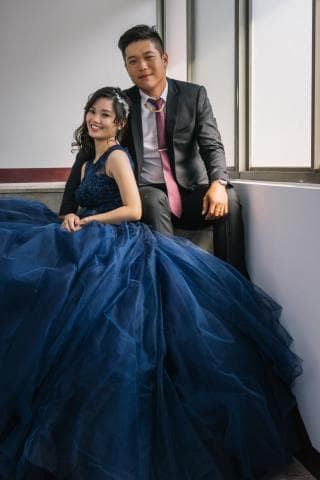 這張照片是一對新人在婚禮上，新娘穿著一件藍色的婚紗，新郎則穿著一套黑色的西裝。