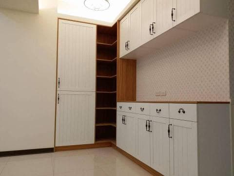 這張照片是一間房間的角落，有一個白色的儲物櫃，櫃子上有黑色的把手，看起來很乾淨整潔。