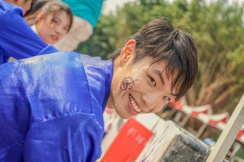 這張「一個年輕人穿著藍色外套，微笑著看著鏡頭」的照片是。