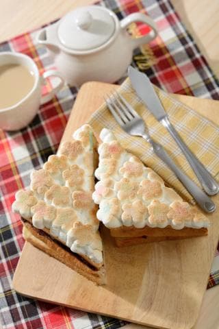 這張照片是一個木頭切菜板，上面放了兩片烤好的吐司，上面塗滿了棉花糖。