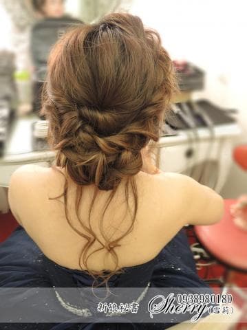 這張照片是一個年輕女性，她有一頭漂亮而時尚的棕色頭髮。她正側身坐在一個椅子上，背對鏡頭，她的頭髮做了一個精緻的髮型，看起來很漂亮。