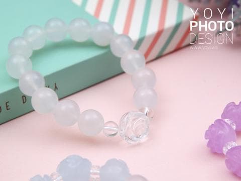 這張照片是一條白色珠子手鍊，手鍊上有一顆水晶玫瑰花造型的珠子，非常精緻。