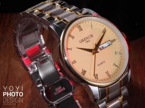 這張照片是一個金色和銀色的手錶。手錶的錶盤是淺色的，上面有黑色的數字和指針，以及 GRENCH 1861 的品牌名稱。錶盤上還有 QUARTZ 和一個日期顯示窗。