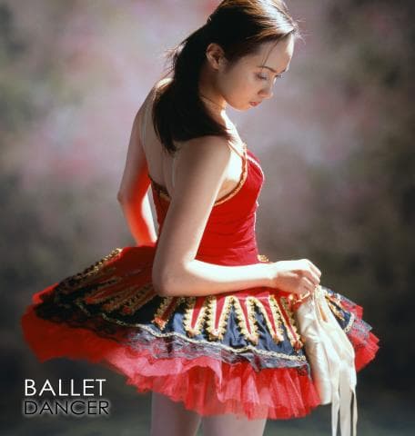 這張「芭蕾舞者」的照片是一個穿著紅色舞裙的年輕女孩，她正舉著一隻芭蕾舞鞋。