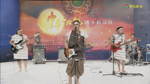 這張「樂團在舞臺上表演」的照片是，四個穿著傳統服裝的樂手，正在演奏音樂，他們身後是紅色的背景和一個大大的月亮，他們看起來非常投入。