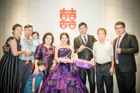 這張照片是一對新人結婚的合照，最重要的是新郎新娘，他們穿著華麗的禮服，站在中間，笑容滿面，看起來非常幸福。