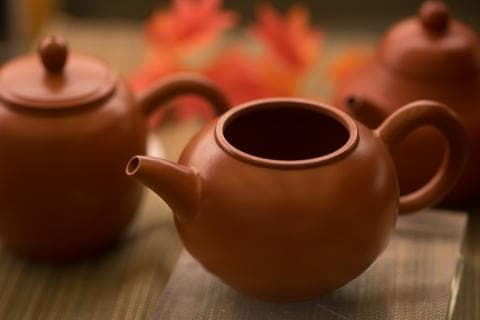 這張「茶壺」的照片是三個陶製茶壺，其中一個茶壺的蓋子是打開的，另一個茶壺是完整的，第三個茶壺是特寫。