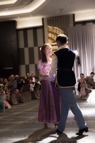 這張婚禮的照片是一對新人正在跳舞，男方穿著深藍色的西裝，女方穿著紫色的禮服，背景是婚禮宴會的場地。