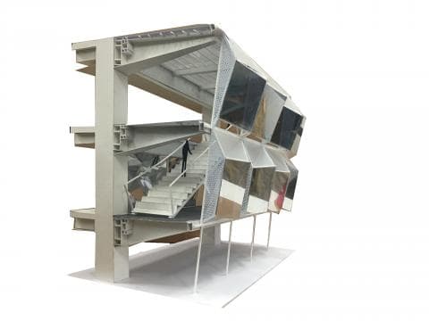 這張照片是一個模型建築，其中最重要的部分是建築的正面。它由多個不同形狀的玻璃窗構成，形成一個錯綜複雜的幾何圖案，每個玻璃窗都反射著周圍環境的光線，使建築顯得更加生動有趣。