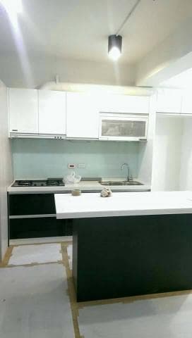 這張照片是一個現代化的廚房，最重要的是黑色的中島吧台。它有白色的人造石台面，下方是深黑色的櫃體。